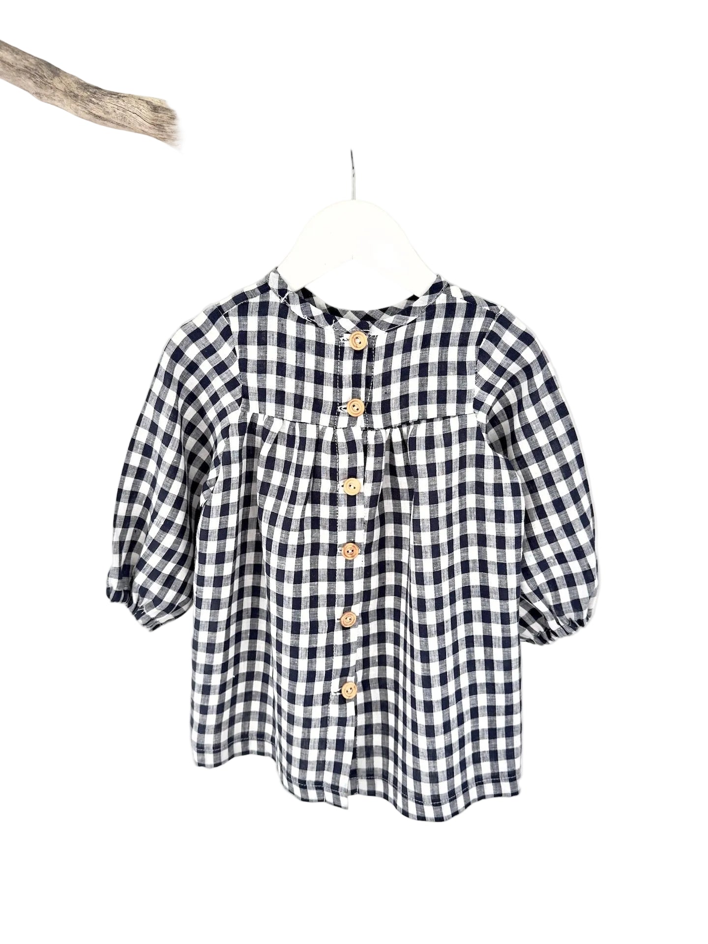 A navy and white checkered long sleeve dress for children, displayed on a hanger.