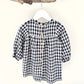 A navy and white checkered long sleeve dress for children, displayed on a hanger.