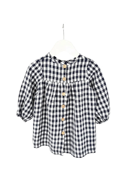 A navy and white checkered long sleeve dress for children, displayed on a hanger.